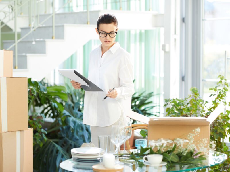 Serious busy attractive young female manager responsible for delivery checking goods and making notes about products in paper, she preparing restaurant for opening